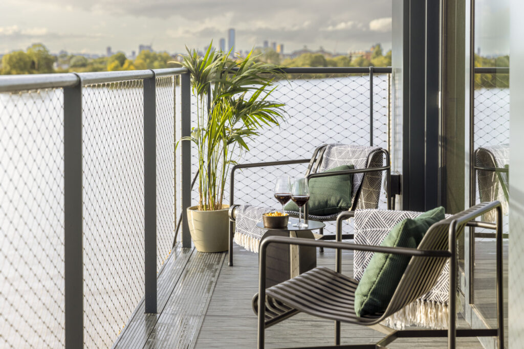 two chairs on balcony with two glasses of red wine and the view of the river thames